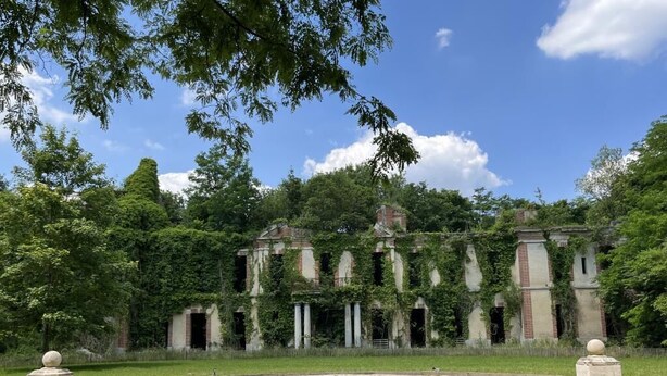 Un bâtiment historique doté d’une vaste cour intérieure, entouré d’une végétation luxuriante et d’arbres.