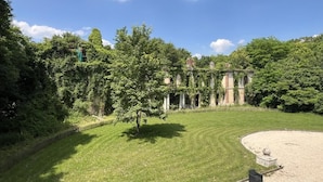 Un bâtiment historique à l’architecture classique, entouré d’une pelouse bien entretenue et d’arbres.