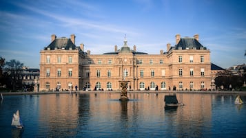 Een groot historisch gebouw met een centrale fontein, die weerspiegeld wordt in een rustig waterlichaam.