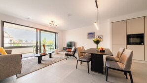 Un comedor moderno con un gran ventanal, un televisor de pantalla plana y una zona de cocina con microondas.