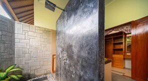 A bathroom with a stone wall, a shower area, and a wooden cabinet. - Villa Linggah Longgah, Bali - Spectacular Clifftop Elegance! (Kabupaten Buleleng)