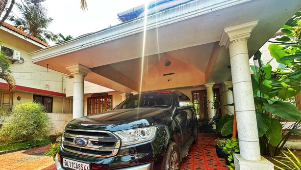 A black SUV parked under a covered area with a tiled floor and columns. - La Casa Luxury AC Villa at Trivandrum City Centre, Just 5 min to Airport (Thiruvananthapuram)