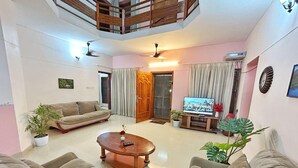 A living room with a sofa, a coffee table, a TV, and a balcony. - La Casa Luxury AC Villa at Trivandrum City Centre, Just 5 min to Airport (Thiruvananthapuram)