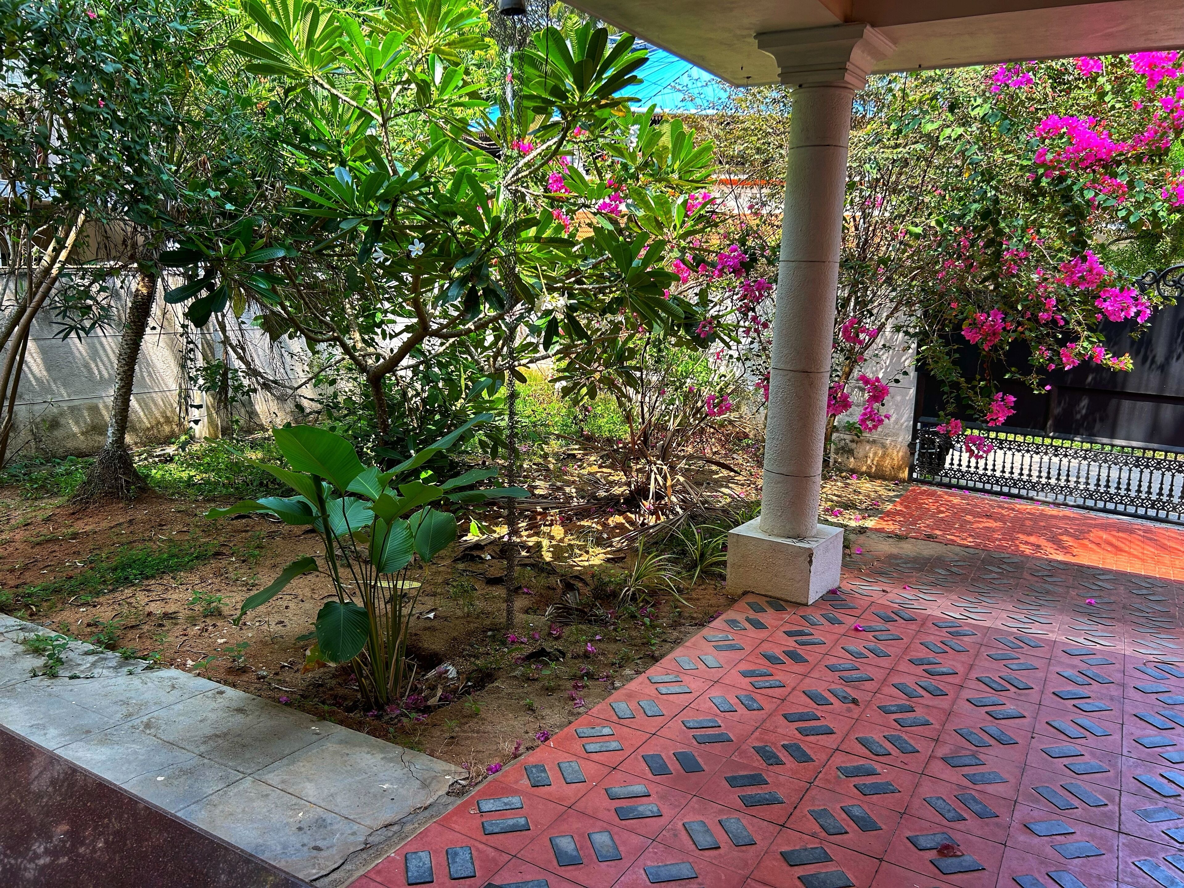 Un espace jardin aménagé avec un chemin pavé, une colonne et des plantes à fleurs.