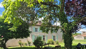 Une maison avec un jardin, un banc et une table.