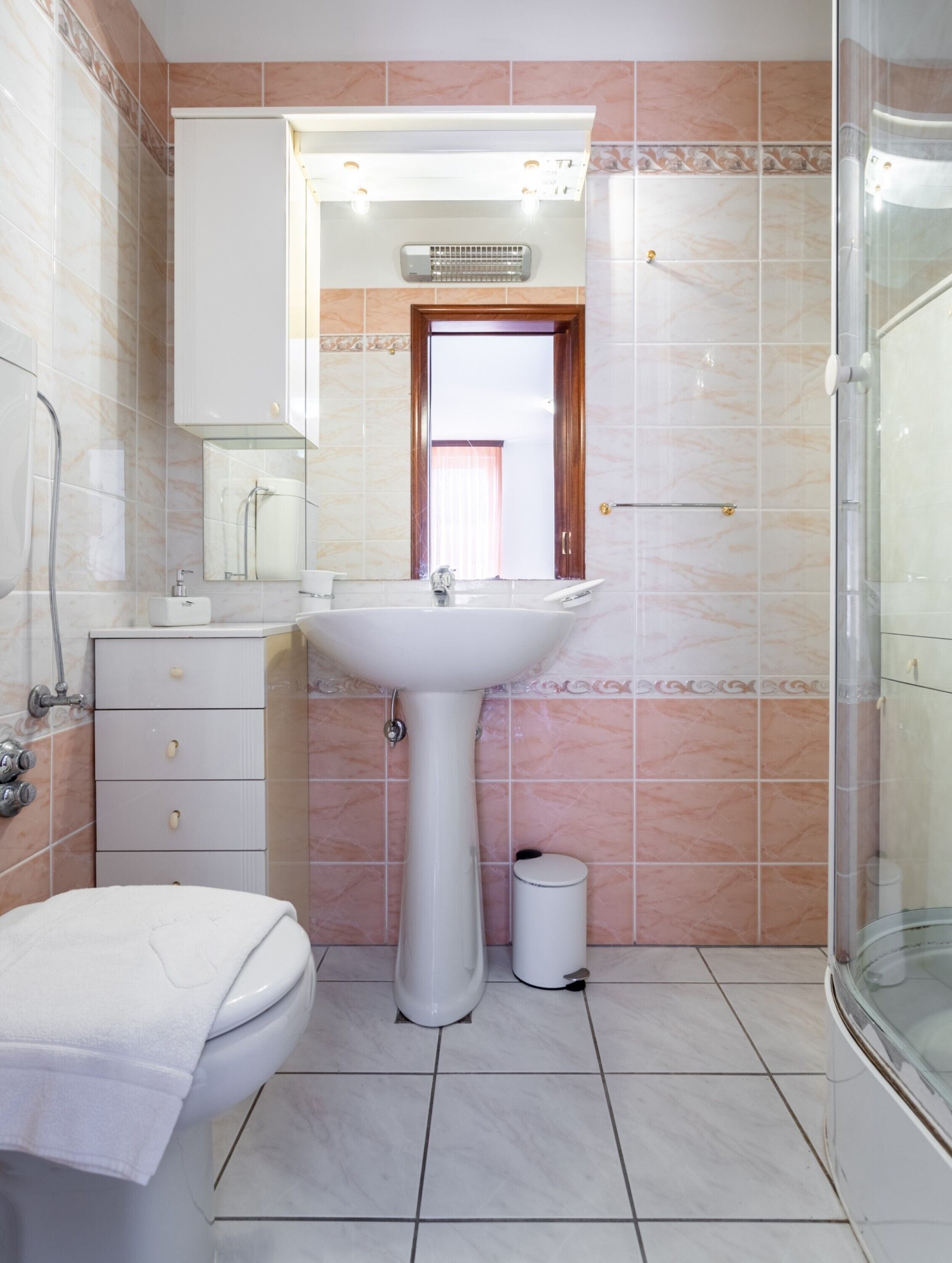 A bathroom with a sink, mirror, and shower.