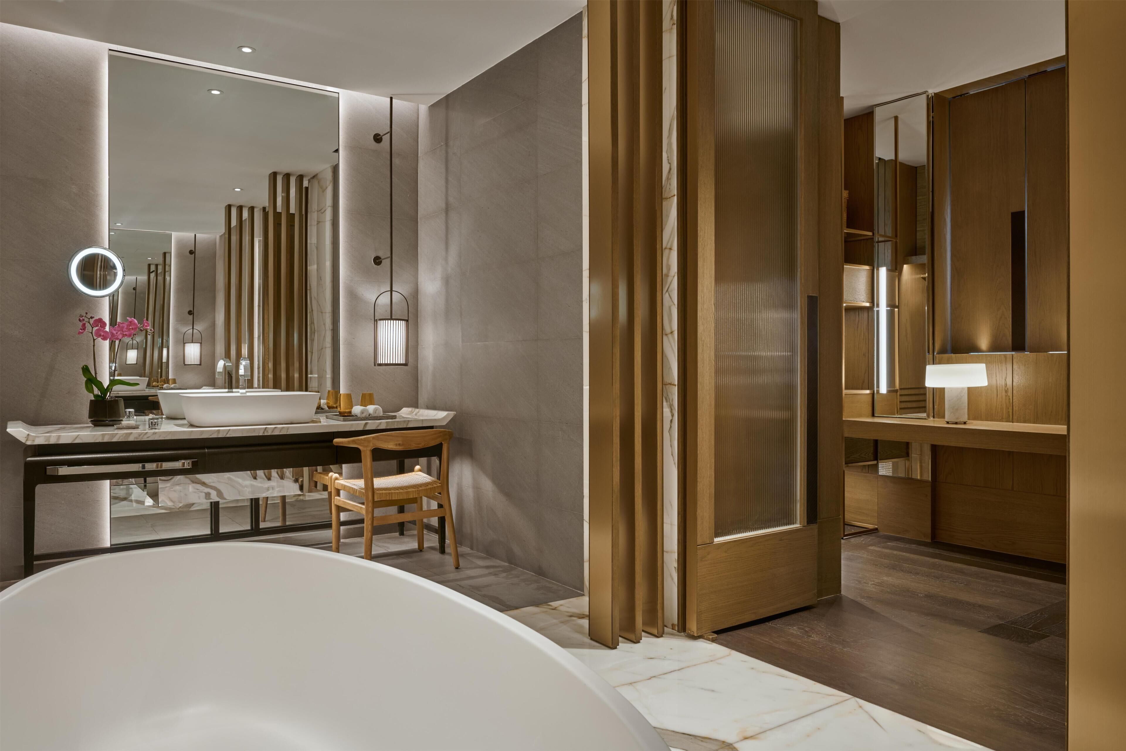 A modern bathroom with a bathtub, vanity, and a large mirror.