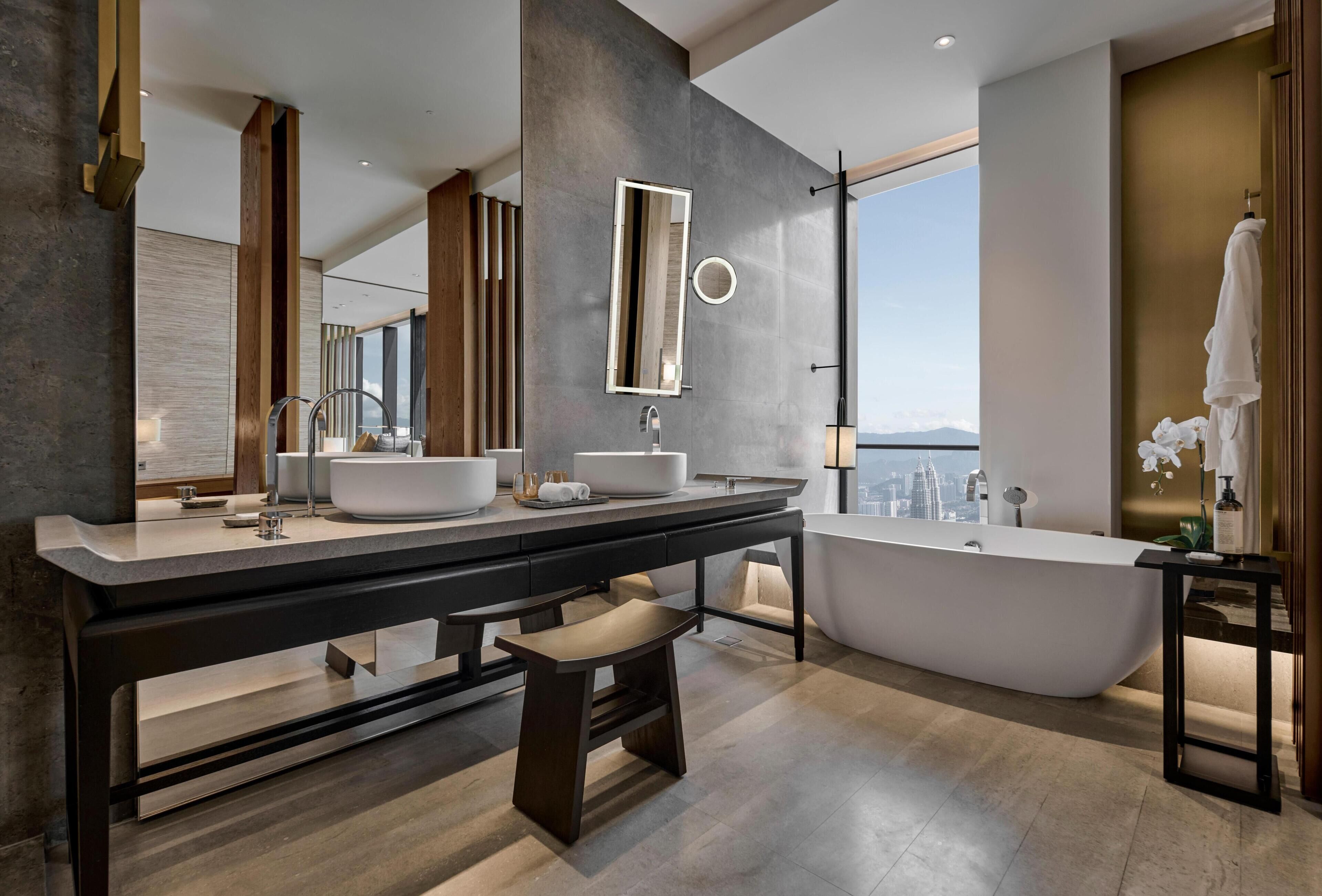 A modern bathroom with a large vanity, two sinks, a freestanding bathtub, and a large mirror.