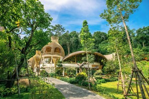 Ein Garten mit einem Weg, der zu einem Gebäude mit Kuppel und überdachtem Bereich führt.