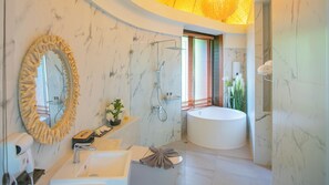 Une salle de bain moderne avec une grande baignoire ovale, un lavabo sur pied, un meuble-lavabo avec un miroir et un espace douche.