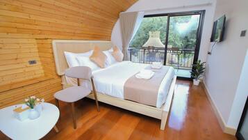 A bedroom with a wooden ceiling, a large bed with white linens, a small table with a vase, and a balcony with a chair and table.
