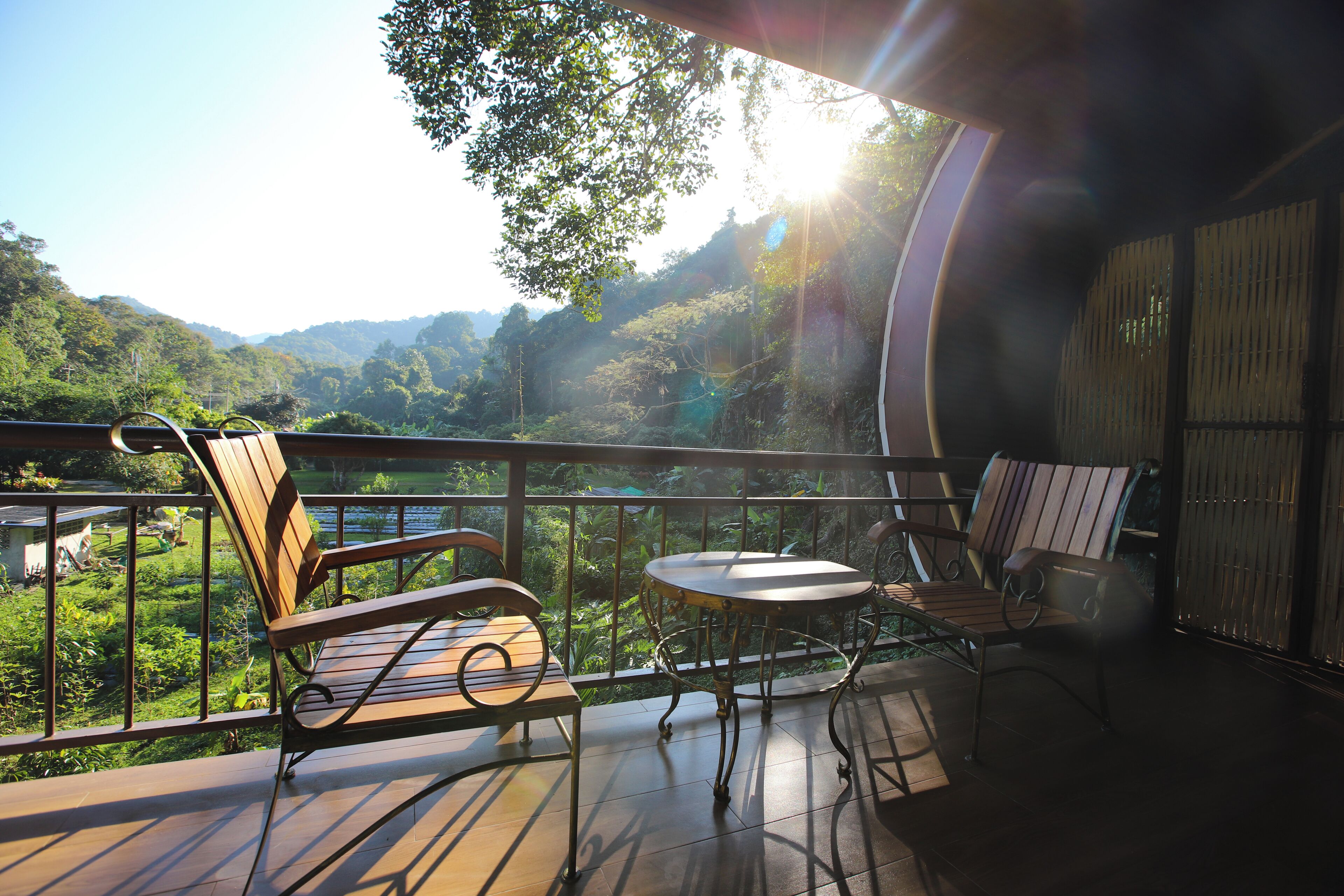 Un balcón con mesa y sillas, con vistas a un paisaje exuberante con colinas.