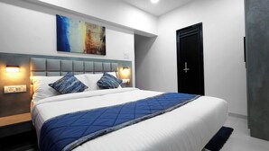 A modern hotel room with a large bed, two bedside lamps, a painting on the wall, and a black door. - Aleta Residency (Mumbai)