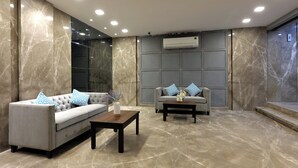 A modern lobby with two sofas, a coffee table, marble flooring, and recessed ceiling lighting. - Aleta Residency (Mumbai)