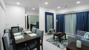 A modern living room with a dining area, a sofa, a coffee table, and a TV. - Aleta Residency (Mumbai)