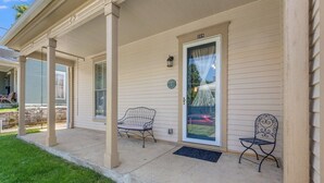 Ein Haus mit einer Veranda, einer Haustür und zwei Gartenstühlen.