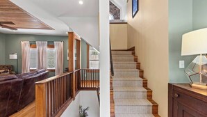 Una escalera con alfombra estampada, barandillas de madera y una lámpara sobre un mueble de madera.