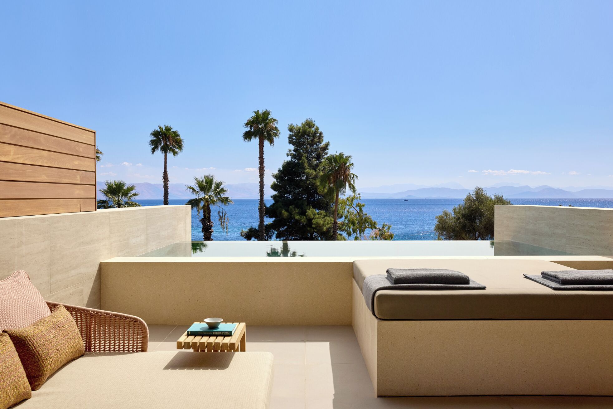 Un área de estar moderna al aire libre con vistas al mar y a las montañas.