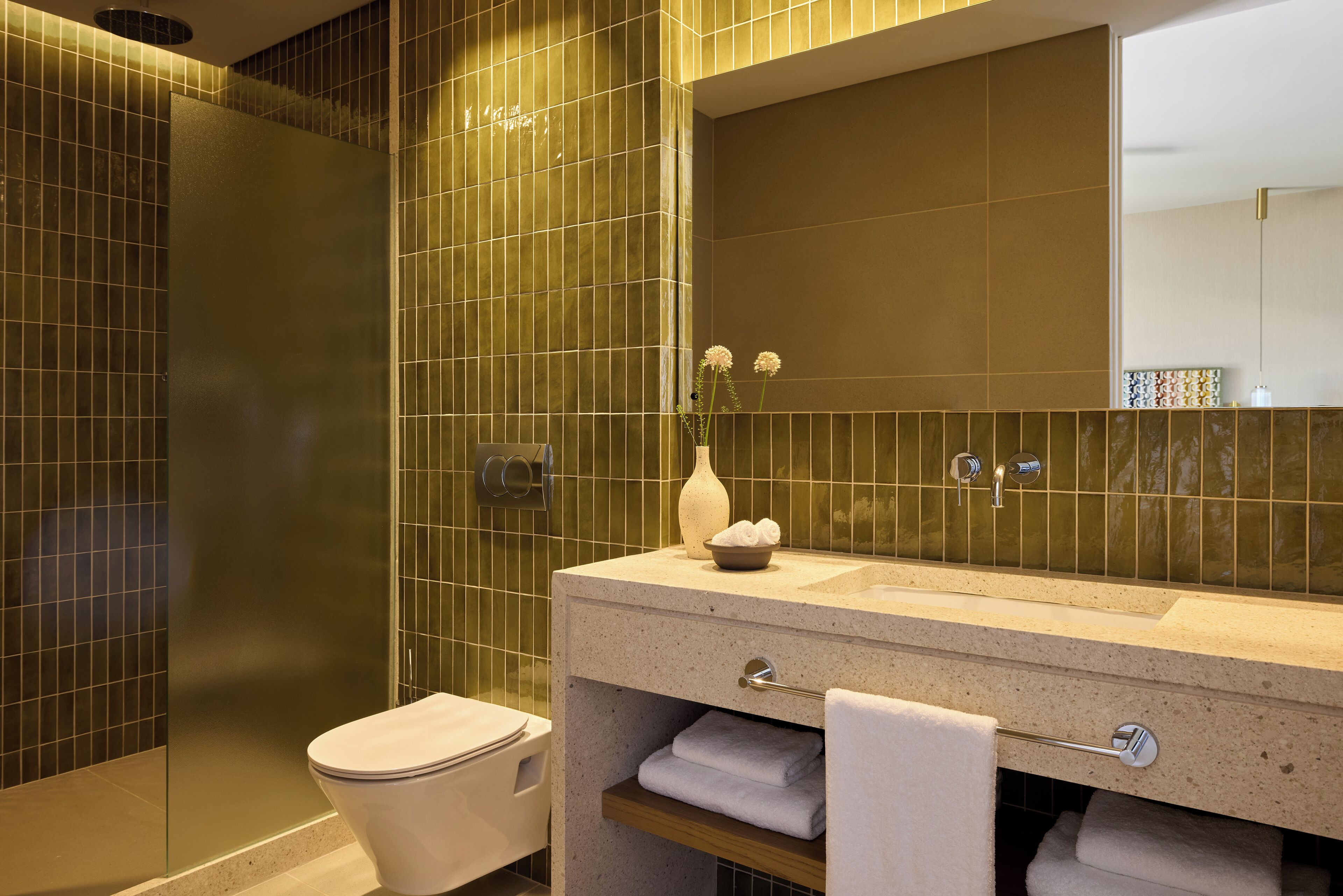 A modern bathroom with a glass shower enclosure, a sink with a mirror, and a towel rack.