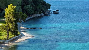 A coastal landscape with a clear view of the sea, a sandy beach, and a grassy area with trees. - Avali, Mar-Bella Collection (Corfu)