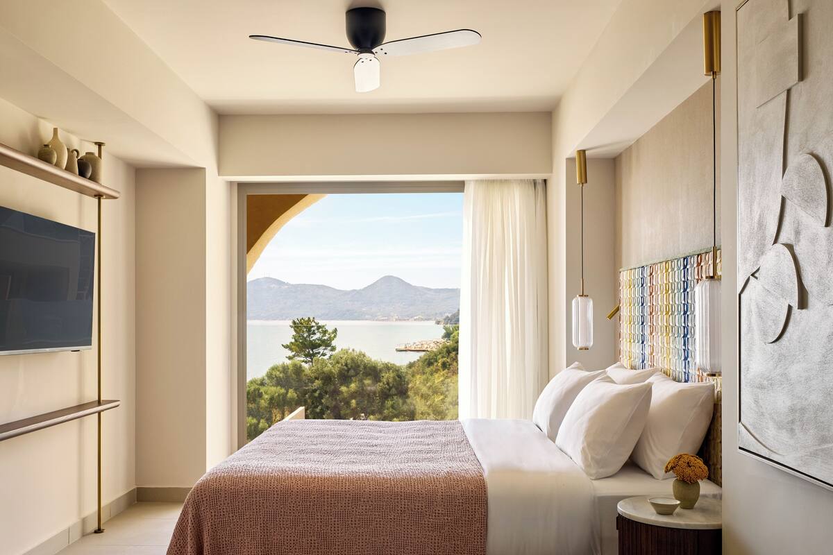 Une chambre avec un grand lit, une télévision et une vue sur un lac et des montagnes.