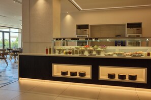 Un espace buffet proposant une variété de plats et une vitrine réfrigérée.
