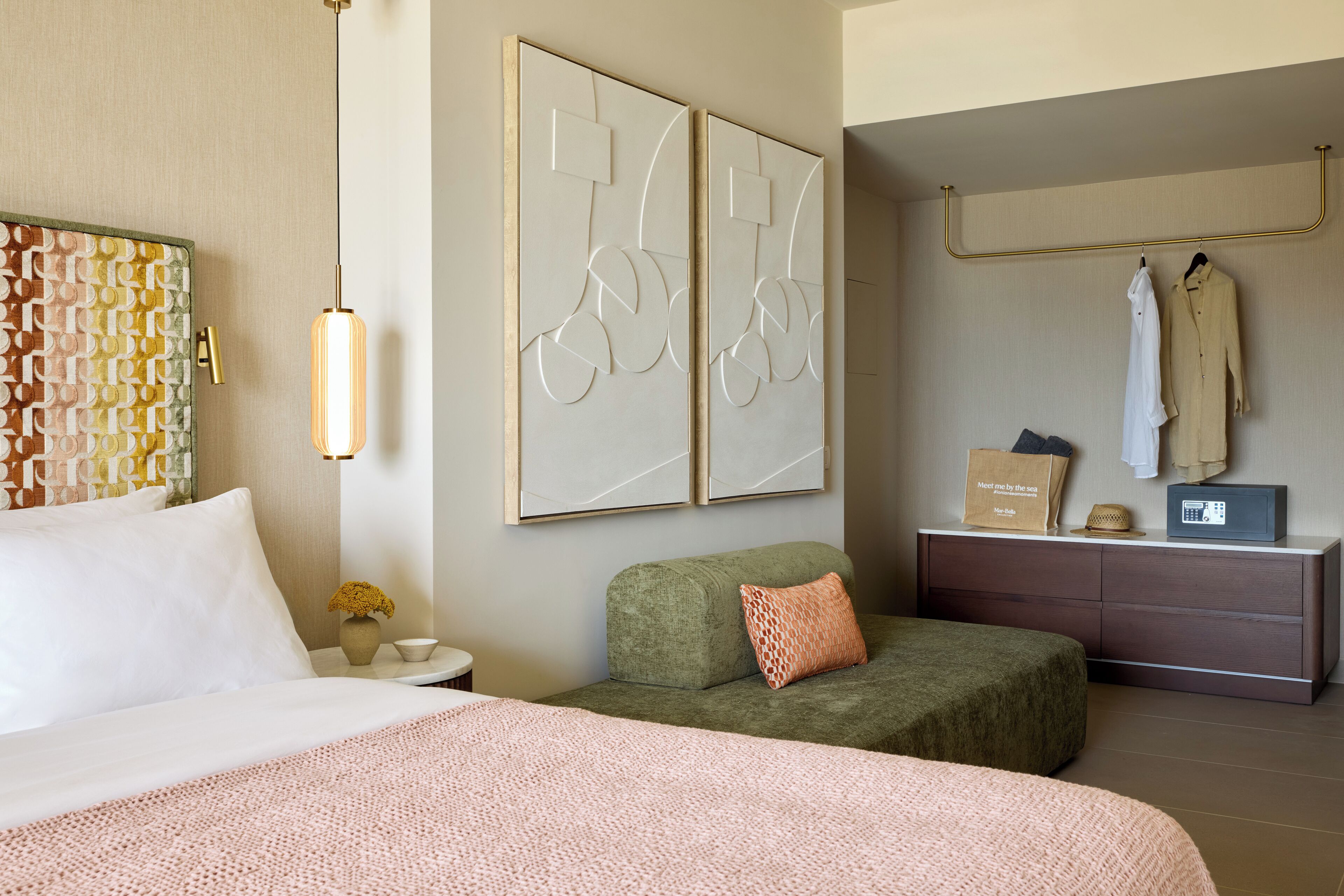 A hotel room with a bed, a green sofa, a dresser, and a wall-mounted radio.