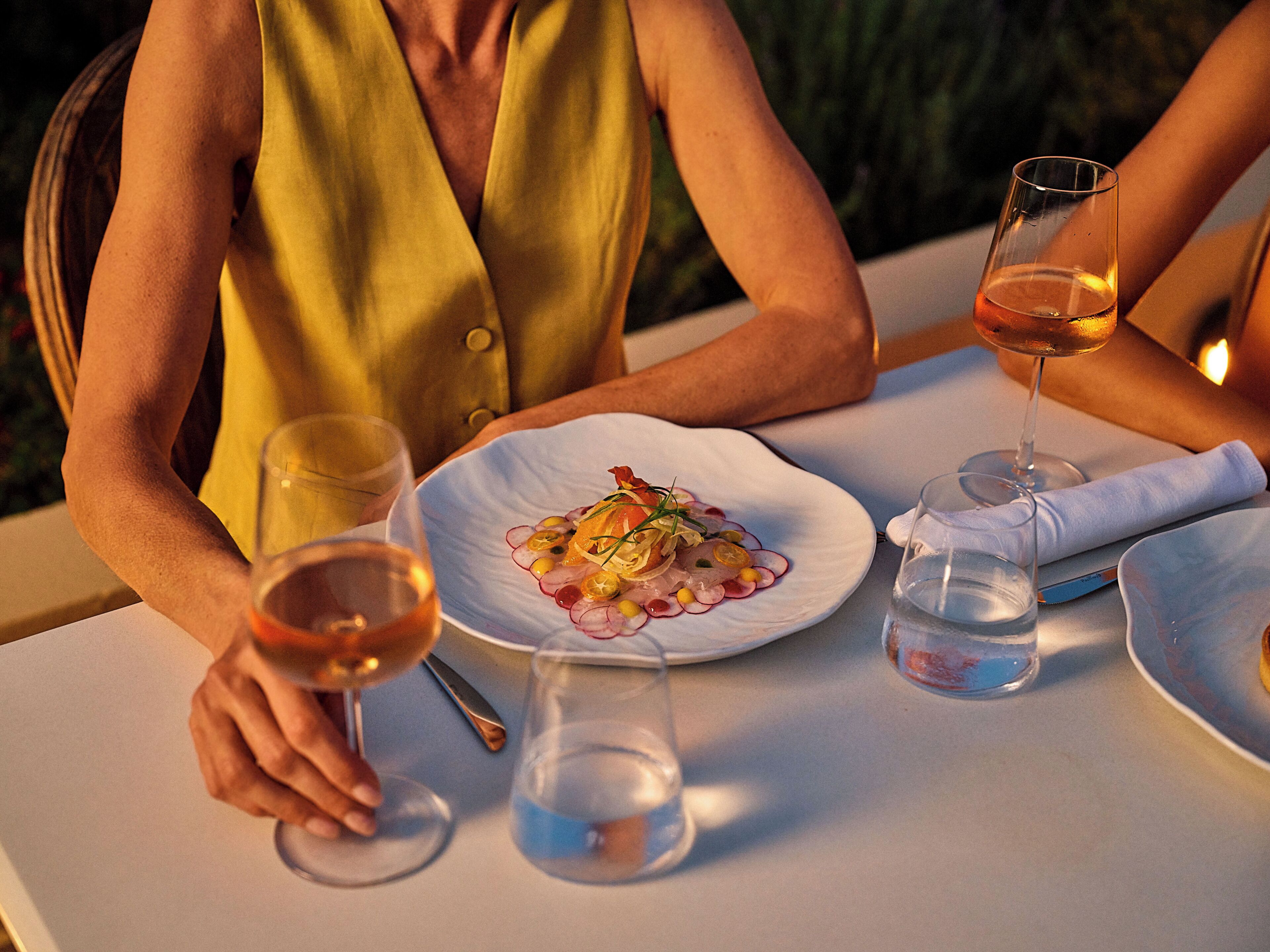 Une table à manger avec une assiette de nourriture, deux verres de vin et un verre d’eau.