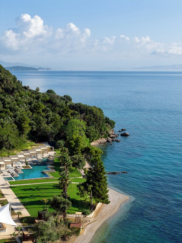 Ein Resort mit Pool, grünen Rasenflächen und Strand.