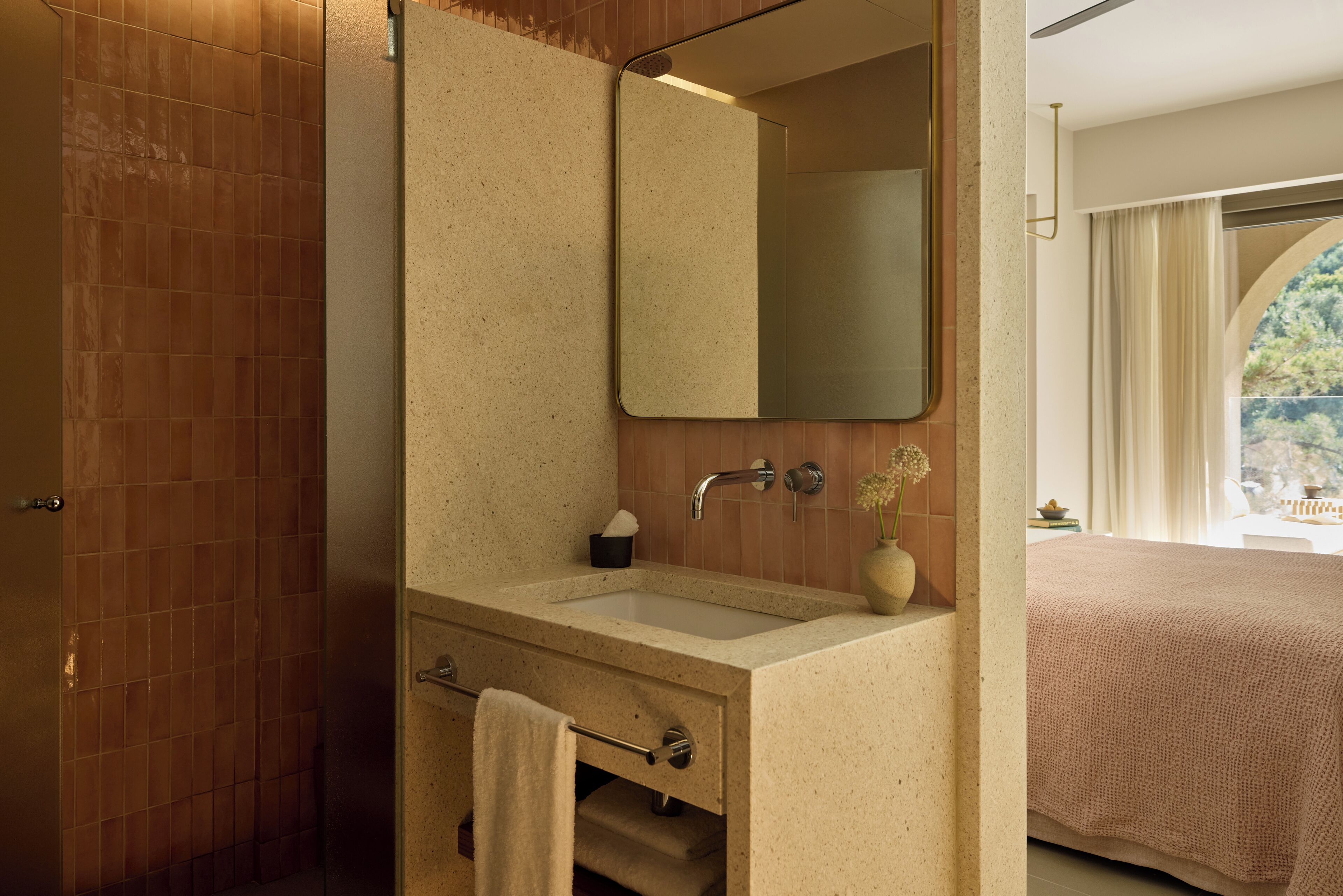 Un baño con un lavamanos color crema, un espejo y un perchero para toallas.