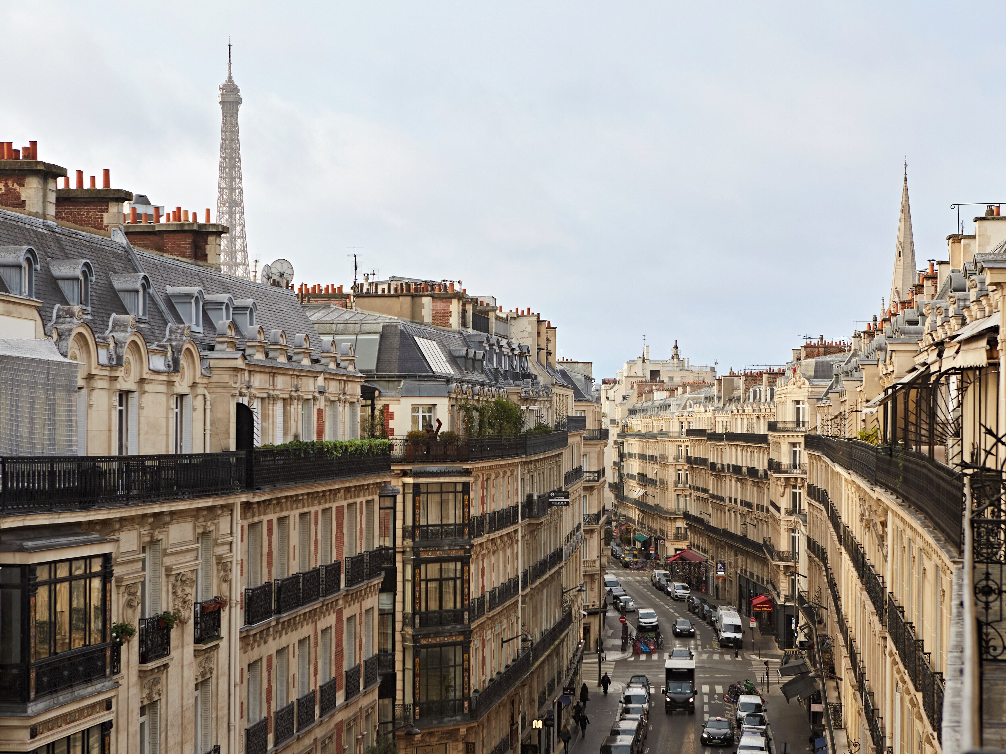 Une vue de rue de Paris, avec des bâtiments historiques, une tour et une rue animée.