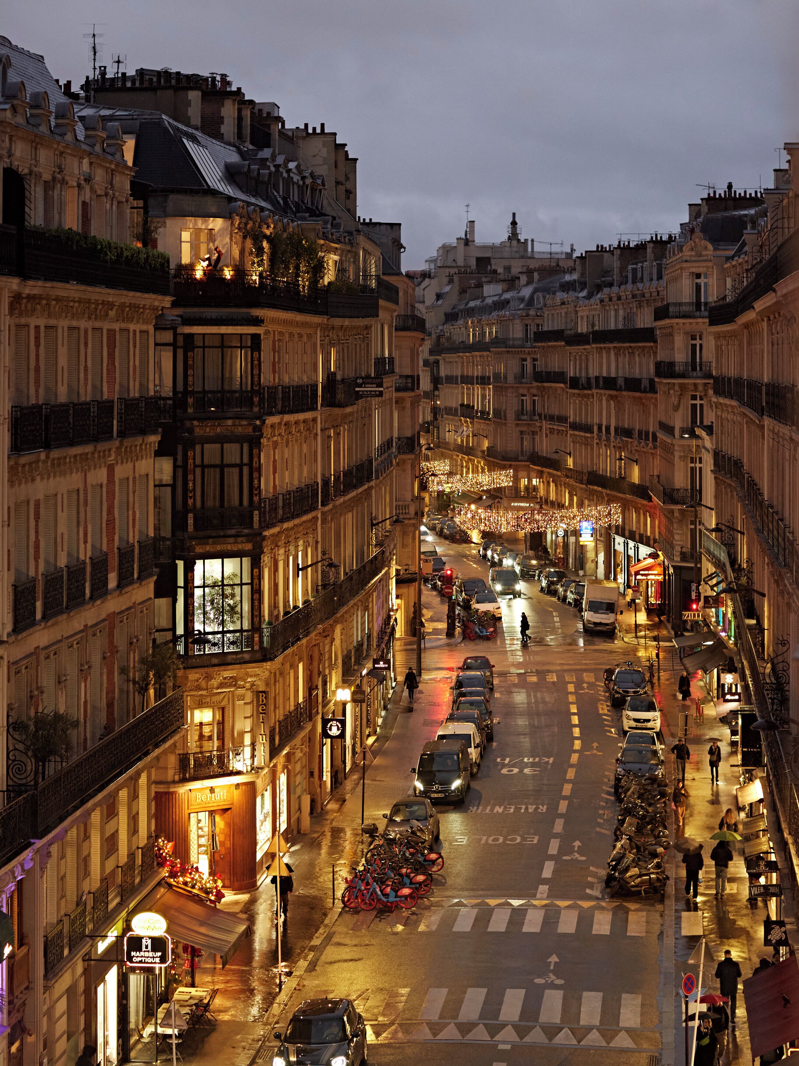 Vista de una calle en una ciudad, con edificios, automóviles y peatones.