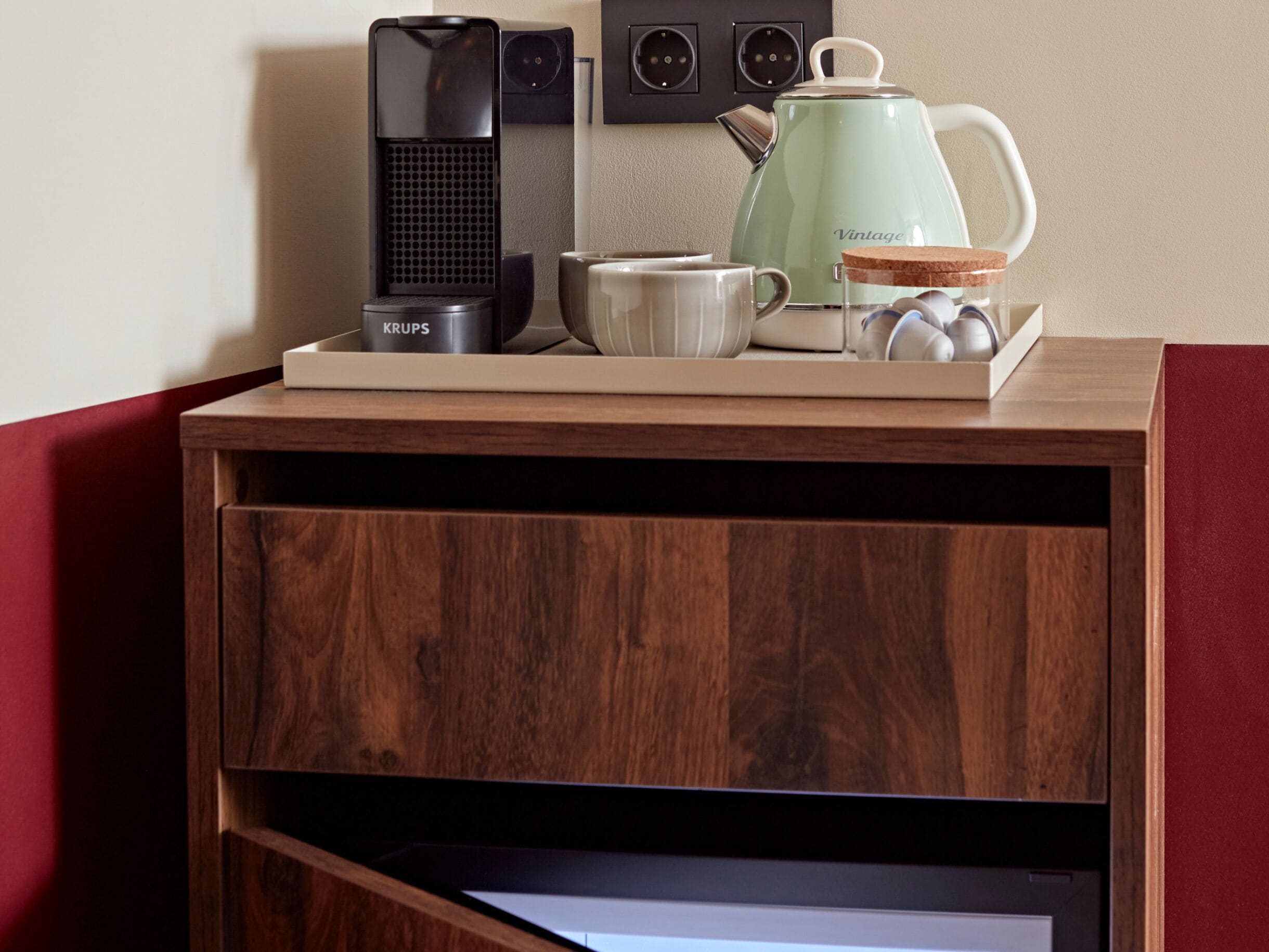 A wooden coffee table with a coffee maker, a kettle, and a mug on it.