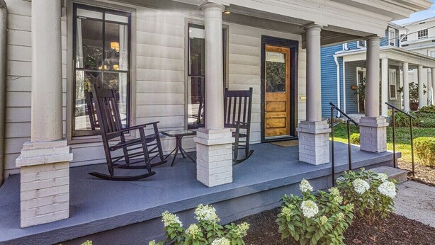 A porch with white columns, a wooden rocking chair, and a bench. - This house is a 2 bedroom(s), 2 bathrooms, located in Frankfort, KY. (Frankfort)