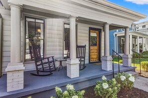 A porch with white columns, a wooden rocking chair, and a bench. - This house is a 2 bedroom(s), 2 bathrooms, located in Frankfort, KY. (Frankfort)