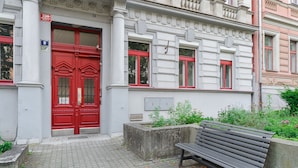 En rød dør med et nummer, en bænk og en plantekasse med planter.