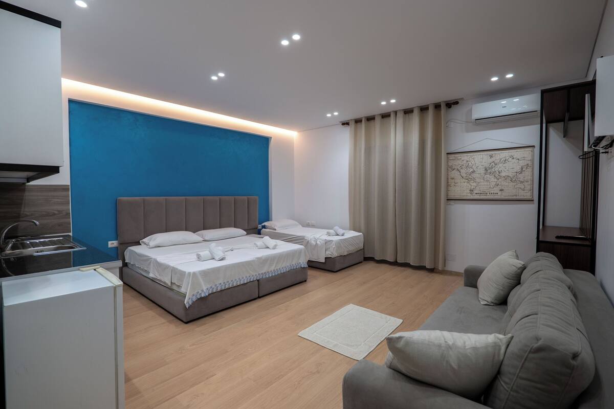 Une chambre d’hôtel moderne équipée d’un lit, d’un canapé, d’un coin cuisine et d’une carte accrochée au mur.