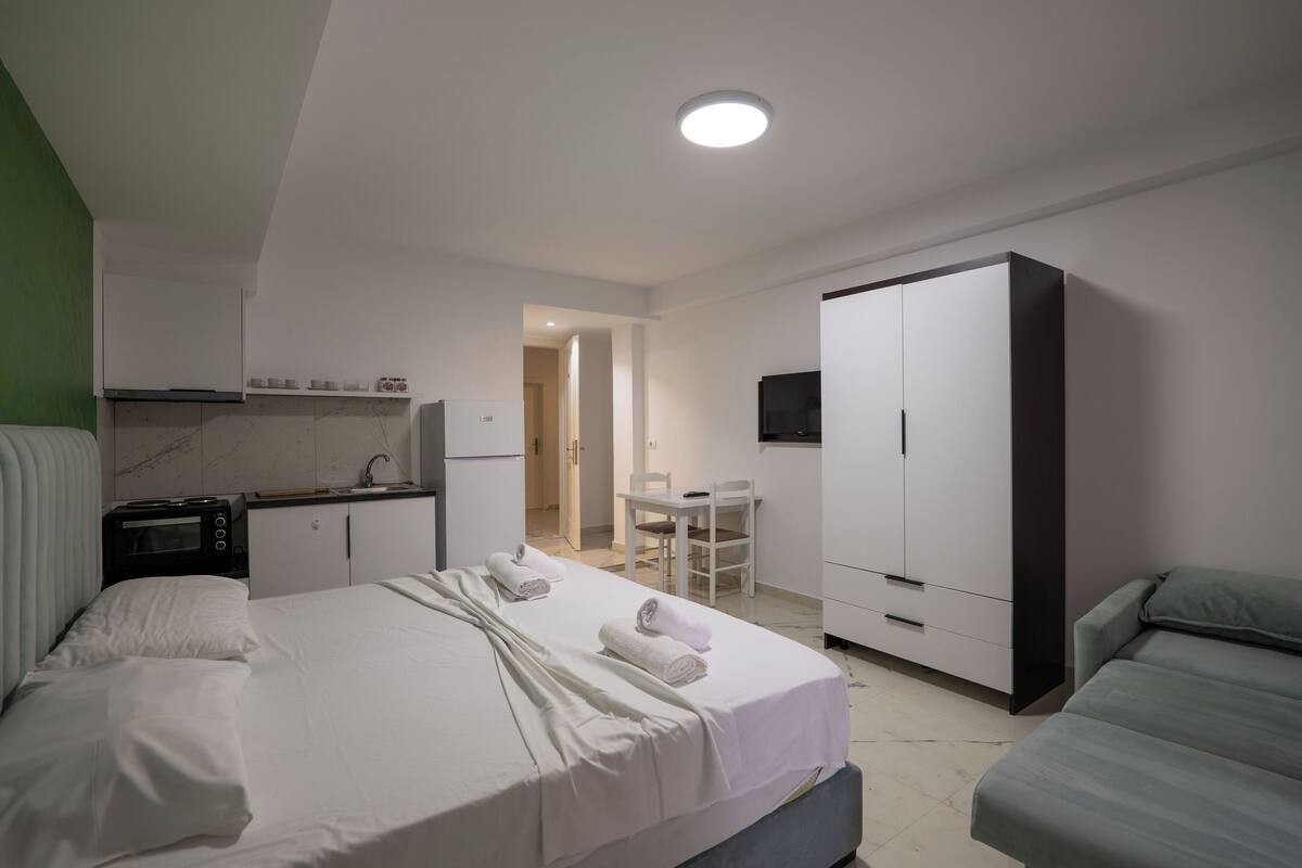 Une chambre d’hôtel comprenant un lit, une kitchenette, une armoire, une télévision et un coin salon.
