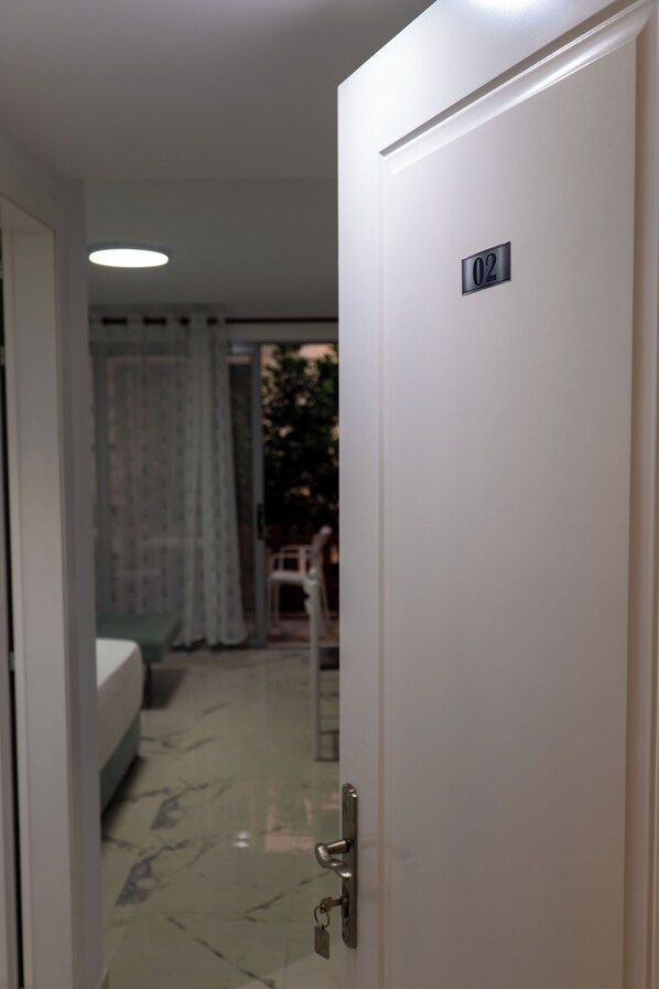 A hotel room with a bed, a door with a number plate, and a view of the outside. - Star&Sea Saranda (Sarandë)