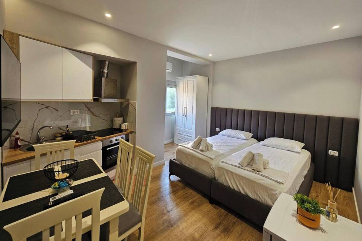 Une chambre d’hôtel compacte comprenant un coin cuisine, un lit avec deux oreillers, une petite table et une chaise.