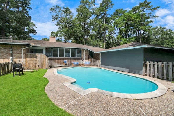 Ein Garten mit Pool, Grill und überdachter Terrasse.