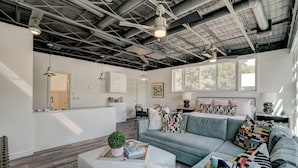 A modern living room with a grey sofa, white pouf, and a coffee table with a plant. - Studio 3 mins from OU — a semester base without signing a 12-month lease (Norman)