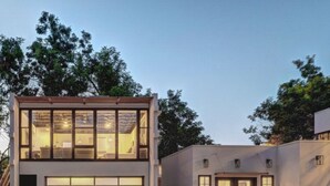 Ein modernes, zweistöckiges Haus mit großer Garage, weitläufigen Fenstern und Einfahrt mit Betonplatten.