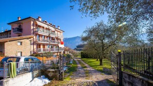 Un edificio a più piani con balconi, un vialetto lastricato e una recinzione.