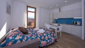 A bedroom with a bed, a desk, and a kitchenette. - Appartamento Blu in Riva del Garda (Riva del Garda)