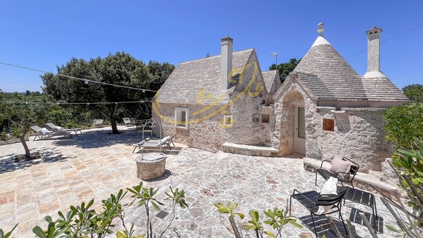 Un bâtiment en pierre doté d’un patio carrelé et d’un espace extérieur aménagé pour s’asseoir.