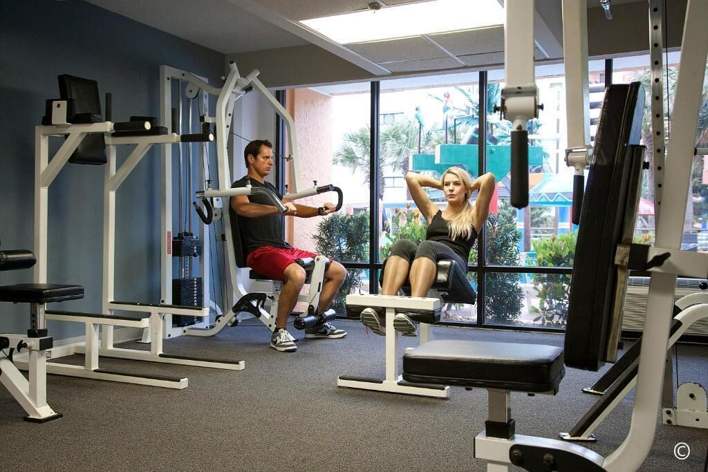 Une salle de sport équipée de matériel d’exercice, dotée de grandes fenêtres et offrant une vue sur l’extérieur.