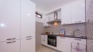 A modern kitchen with white cabinets, a stainless steel range hood, a built-in oven, and a tiled backsplash. - Casa Angerin 1 in Alassio (Alassio)