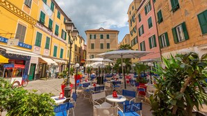 A courtyard with outdoor seating, surrounded by buildings with balconies and shutters. - Casa Angerin 1 in Alassio (Alassio)