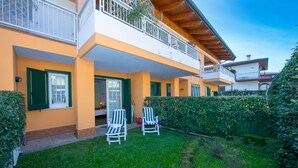 Un bâtiment à deux étages doté d’un balcon, d’un patio couvert et d’un jardin bien entretenu avec deux chaises de jardin.